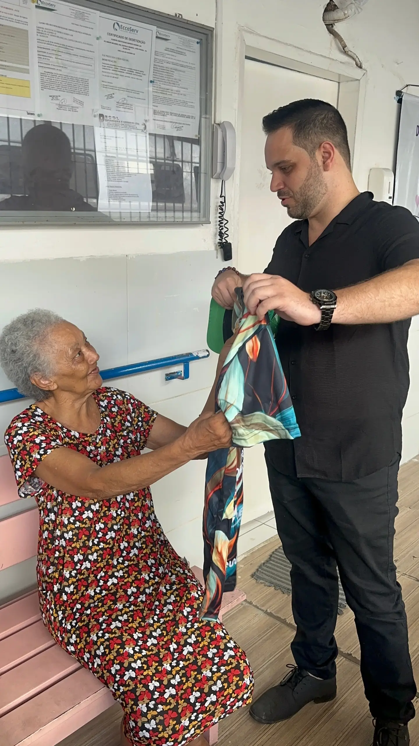 Malory entrega um presente a uma idosa no asilo